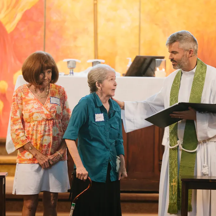 The priest prays a blessing over two members at the front of the church