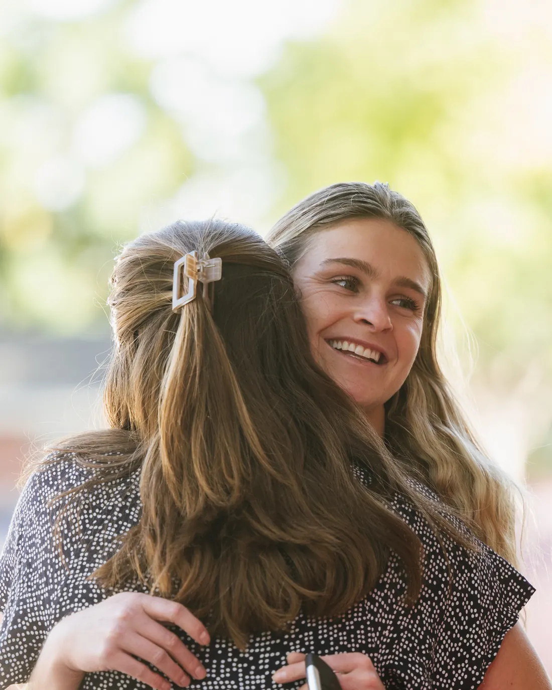 Two women share a warm hug outside after the service
